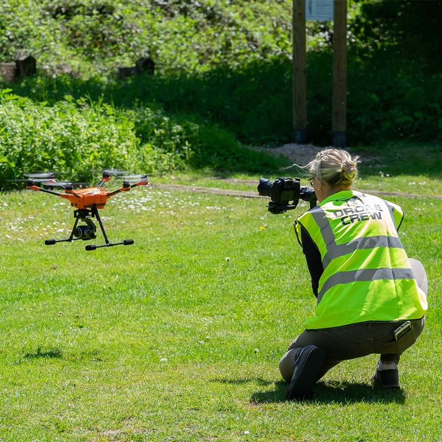 Helen filming on a shoot, with a drone in the air beside her
