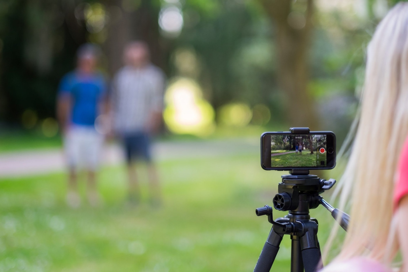 Helen filming two people in a park on a phone on a tripod
