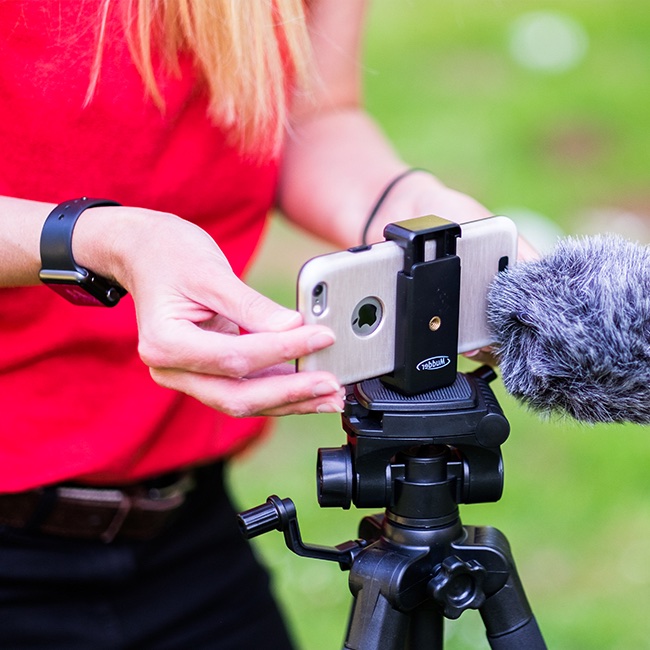 A phone on a tripod with a clip-on microphone, being set up